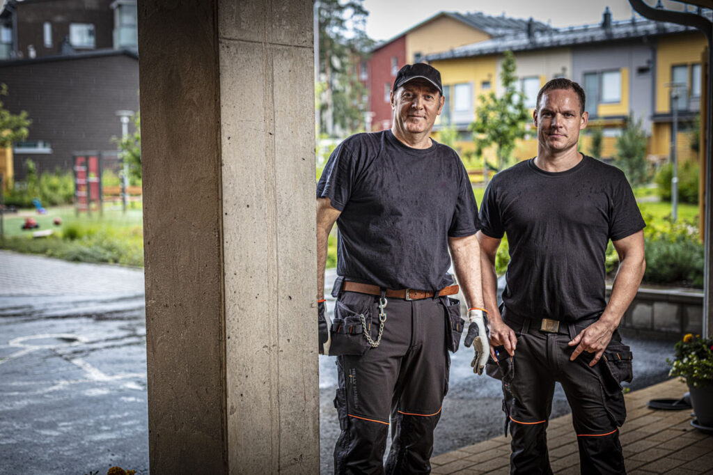 To medarbeidere i arbeidsklær ved inngangen til et bygg