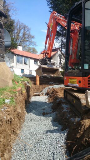 Gravemaskin graver grøft ved et bolighus i Bergen